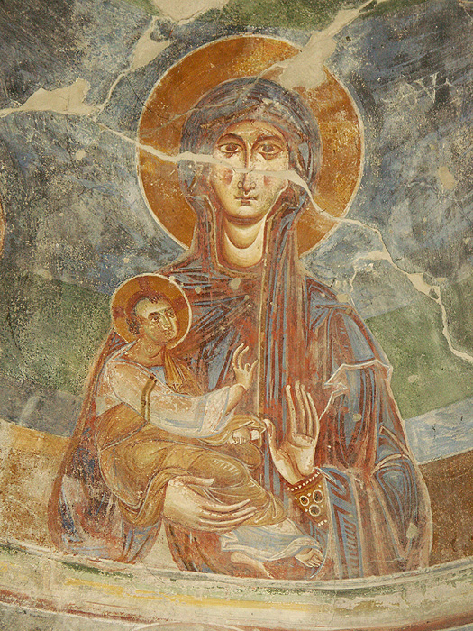Fresco painting of veiled, haloed woman holding child in her right arm. 