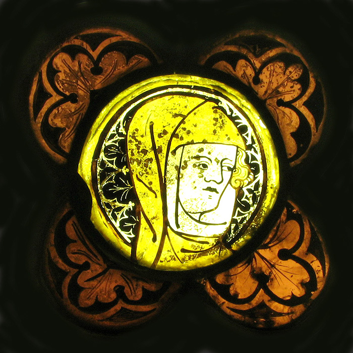 A stained-glass medallion containing a representation of the head of a veiled woman. 