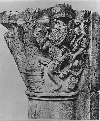 Detail of stone capital containing man carrying a basket of grapes on his shoulders and stepping into a vat of grapes with his left leg. 