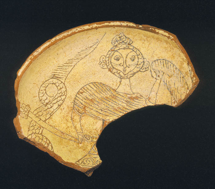 On a fragment of pottery, a bearded figure holds a club and a shield. A scaly tail curls at the left.