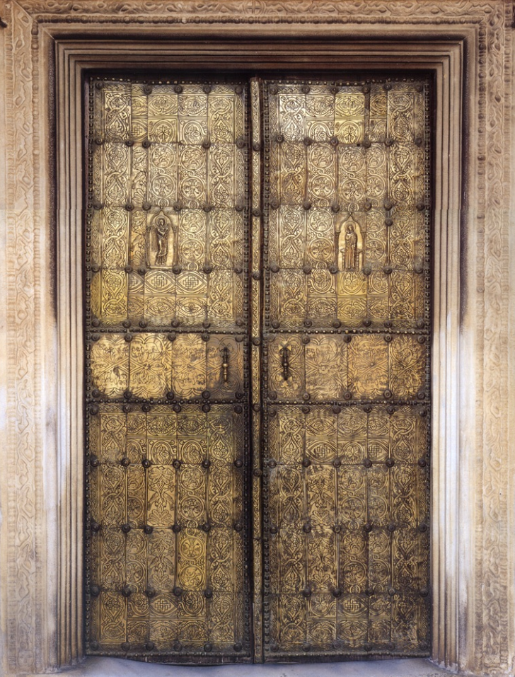 Brass doors with geometric and foliate ornament and the representation of a woman and an angel in the middle section.