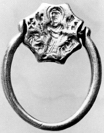 On the obverse of the rotating bezel of a gold ring, a woman with her hands raised stands between two animals and two crosses.