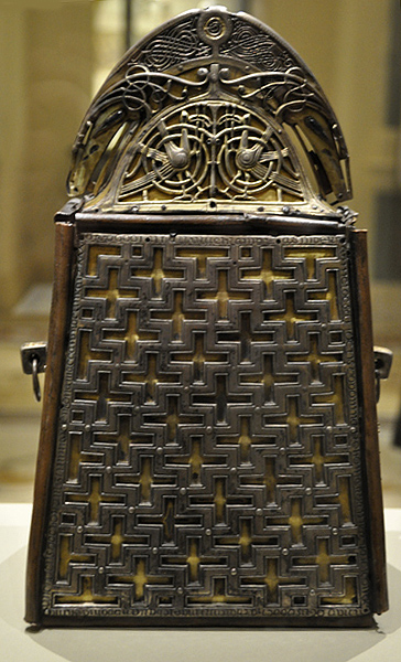 Decorated metal bell case and reliquary with bottom portion in repeating cruciform pattern. Handle decorated with silver and silver-gilt metal interlace ornament and two confronted birds.