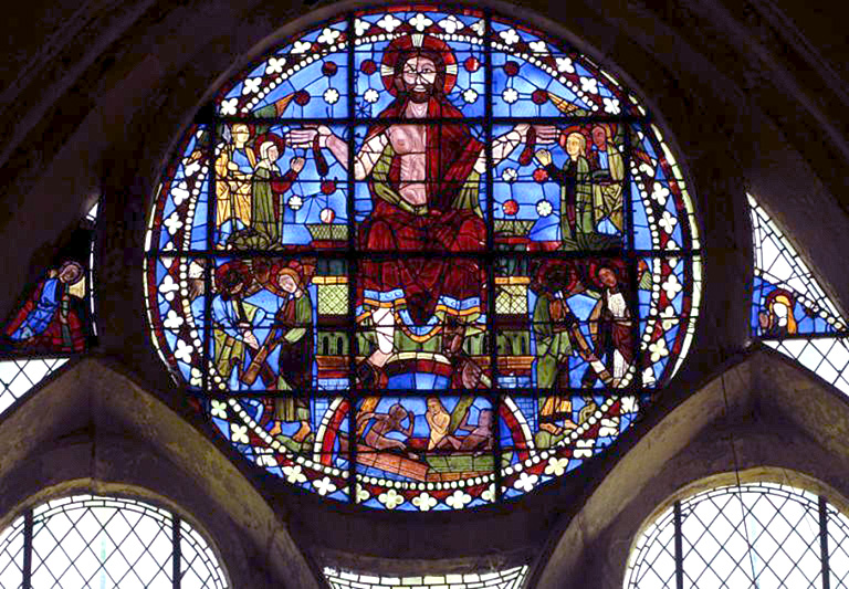 In a stained-glass window, a man on a throne surrounded by several other figures.
