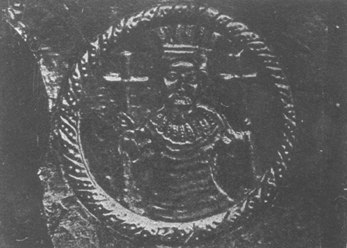 Metal plaque containing medallion with king wearing crown and holding a cross in each hand.
