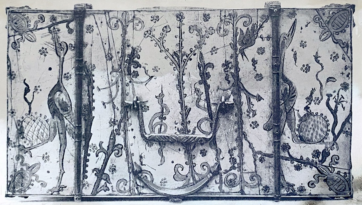 Painted lid of a rectangular ivory casket depicting stylized tree, serpents and crane-like birds amid all over foliate decoration. Metal fittings and handle.