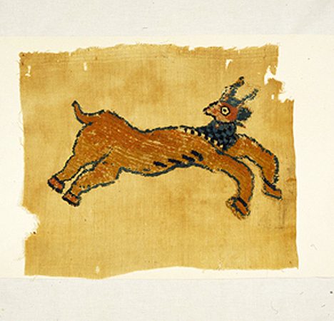 A rectangular textile fragment decorated with a leaping four-legged animal with horns, looking back over its right shoulder. Some edgewear.