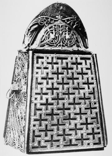 Black and white photograph of decorated metal bell case and reliquary with bottom portion in repeating cruciform pattern. Handle decorated with silver and silver-gilt metal interlace ornament and two confronted birds.