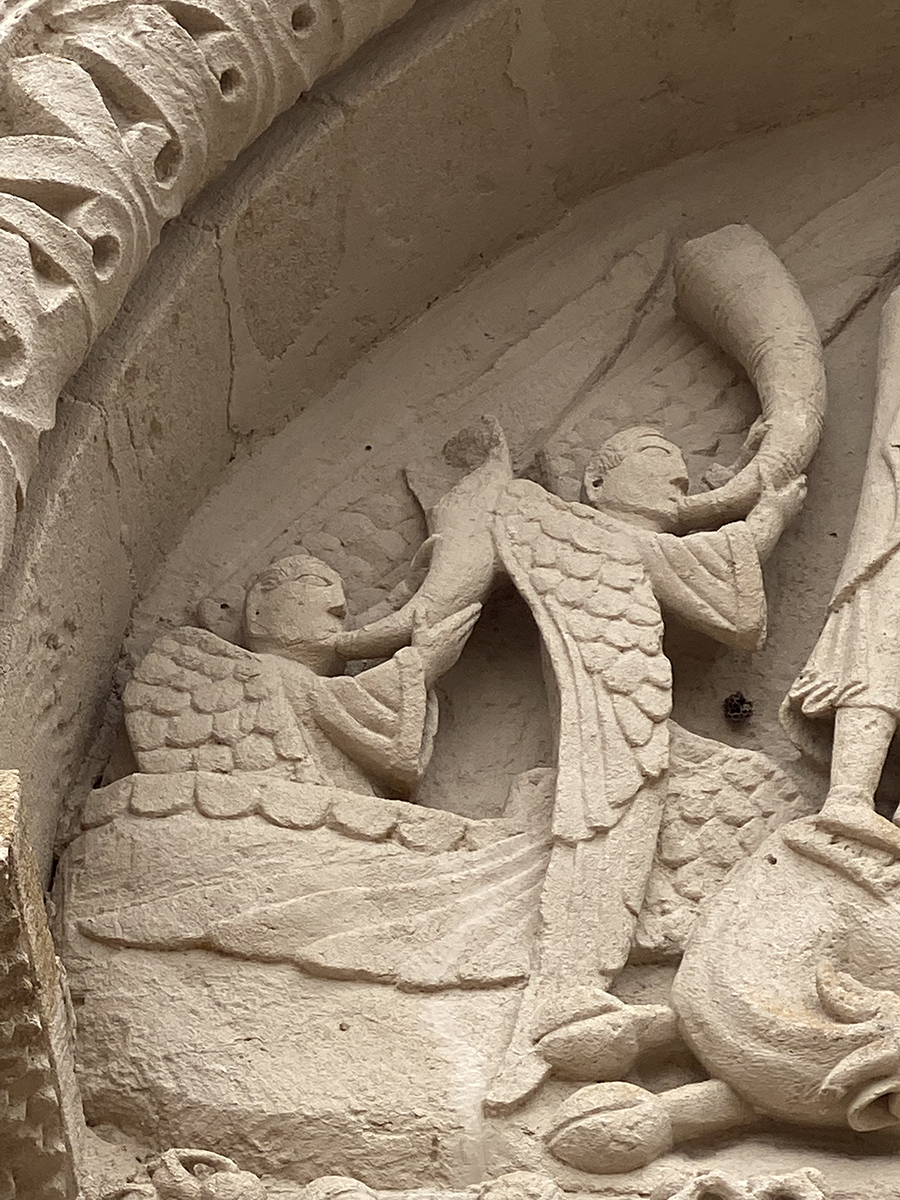 Detail of tympanum relief sculpture showing two angels blowing horns.