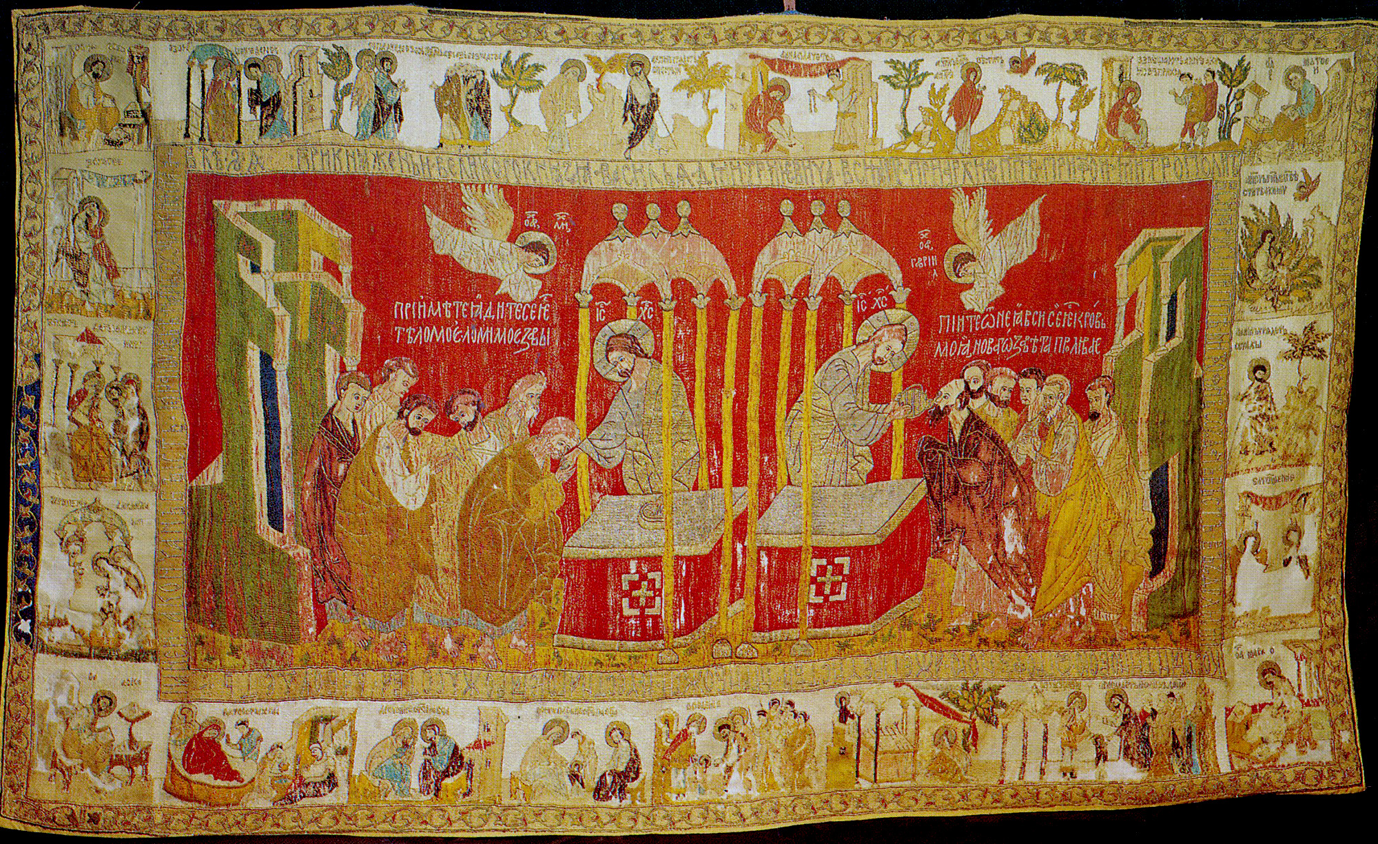 A veil embroidered with a a large center panel with a man standing at an altar and offering bread and wine to groups of other men. A border of smaller scenes surrounds the large center panel.