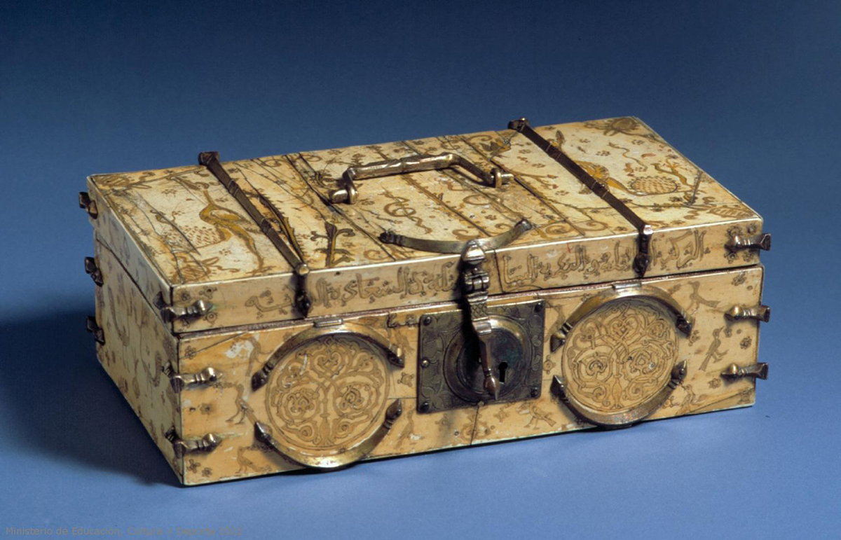 A rectangular ivory box with metal fittings, including a latch in front and a handle on the top. It is painted with animals, plants, and an Arabic inscription.