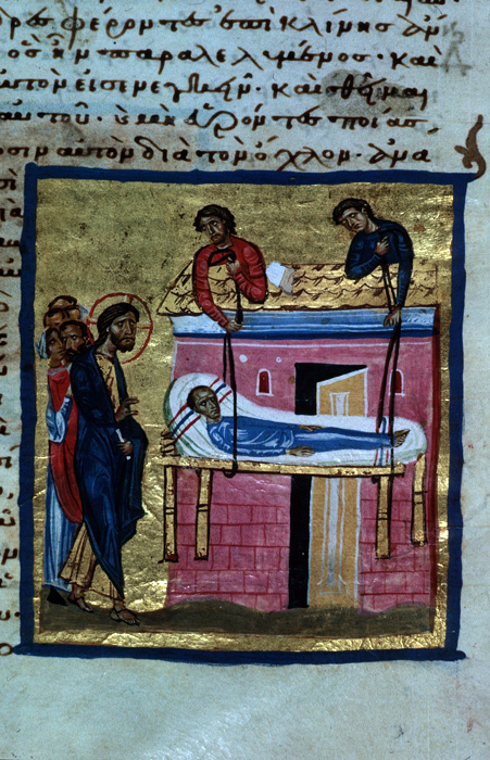Page of manuscript with text and image representing male figure, followed by several people, blesses male figure laying on a bed while being lowered down from a house by two figures. 