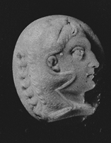 A carved oval, pink and white agate cameo depicting the profile head of a man, looking to right, wearing a lion’s skin over his head. Small chip on lower right portion of the cameo. Black background. 