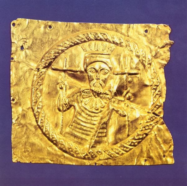 Metal plaque containing medallion with king wearing crown and holding a cross in each hand.