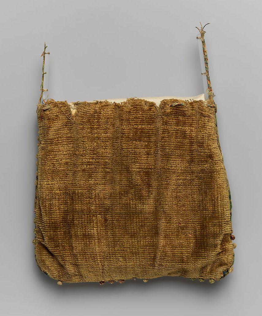 Squarish textile purse made of golden-brown colored fibers on the reverse side. Missing strap and threadbare in some areas.