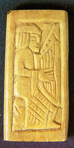 A bone plaque with a seated man playing a harp.