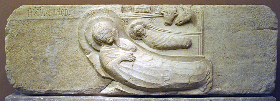A relief sculpture of a woman lying next to a swaddled child with two animal heads above.