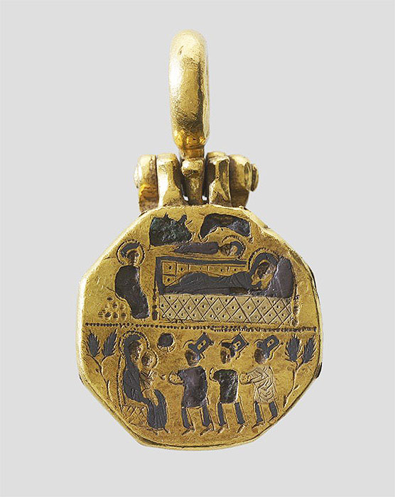 The top cover of a gold reliquary pendant with scenes in two registers. In the upper scene, a figure sits next to two reclining figures below the heads of animals. In the lower scene, three figures approach a figure holding a child.