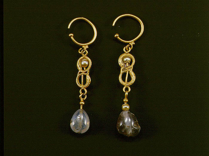 Drop earrings, each containing two gold snakes making a figure-eight form, the upper one encircling a pearl, and a sapphire suspended from base of the lower snake.