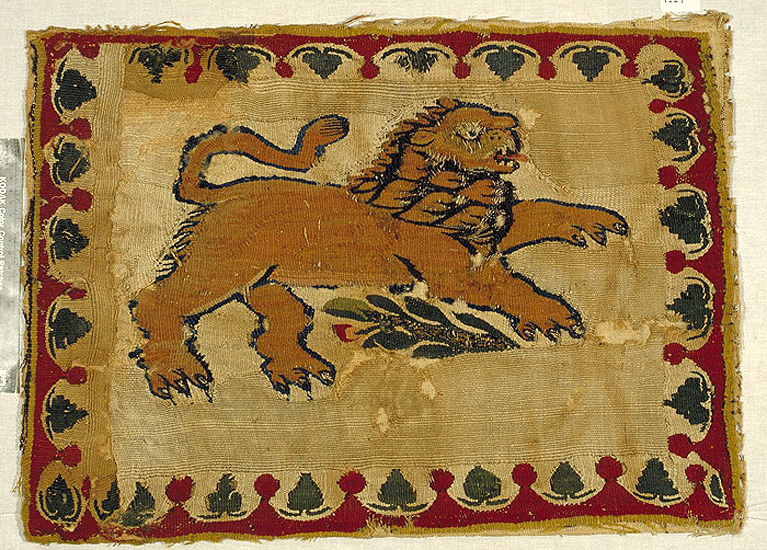 Rectangular textile fragment depicting lion in profile surrounded by red and green foliate border.