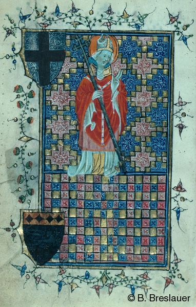 Within a manuscript page, a man dressed as a bishop, who holds a staff in his right hand and raises his left hand. The background consists of two registers with colorful geometric forms and two shield bearing ornament on the left side.