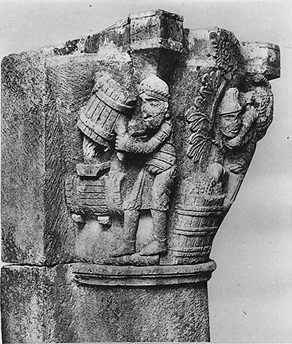 Detail of stone capital containing man pouring liquid out of one barrel into another barrel. 