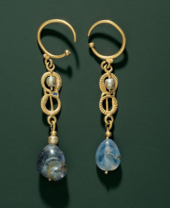 Drop earrings, each containing two gold snakes making a figure-eight form, the upper one encircling a pearl, and a sapphire suspended from base of the lower snake.