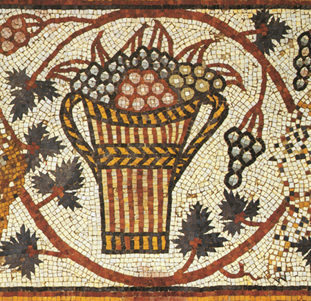 Mosaic detail of a medallion containing a two-handled basket filled with grapes and leaves and surrounded by leafy grapevine with clusters of grapes. White background.