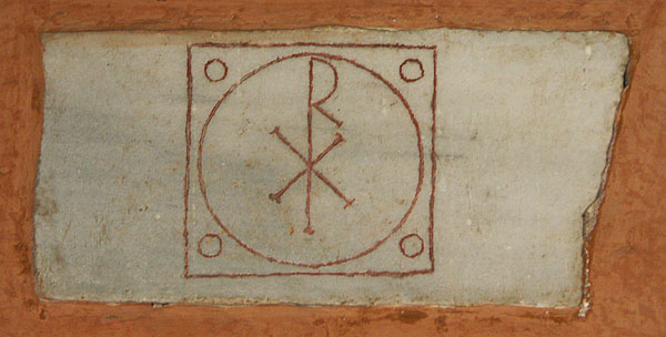 A marble panel that contains an engraved square that encloses five engraved circles. The largest one in the center encloses a monogram of Greek letters.
