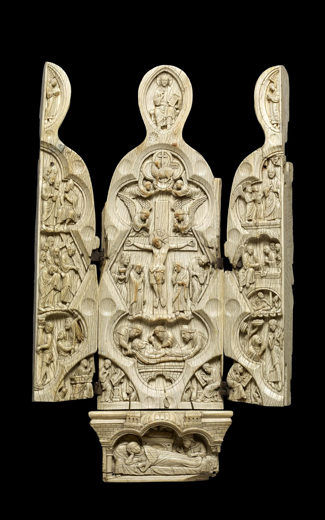 An open ivory triptych carved with many figures in multiple scenes.