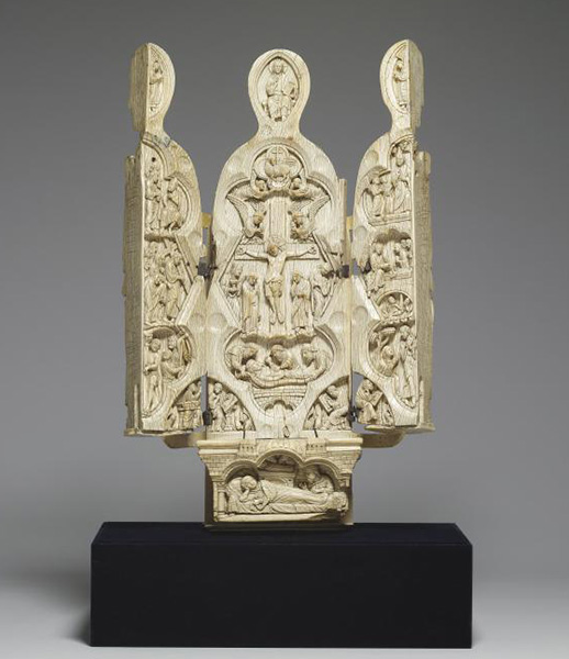 An open ivory triptych carved with many figures in multiple scenes.