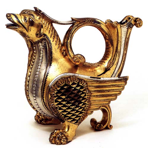 A golden metal vessel in the shape of a dragon with a raised tail and open mouth, facing left.
